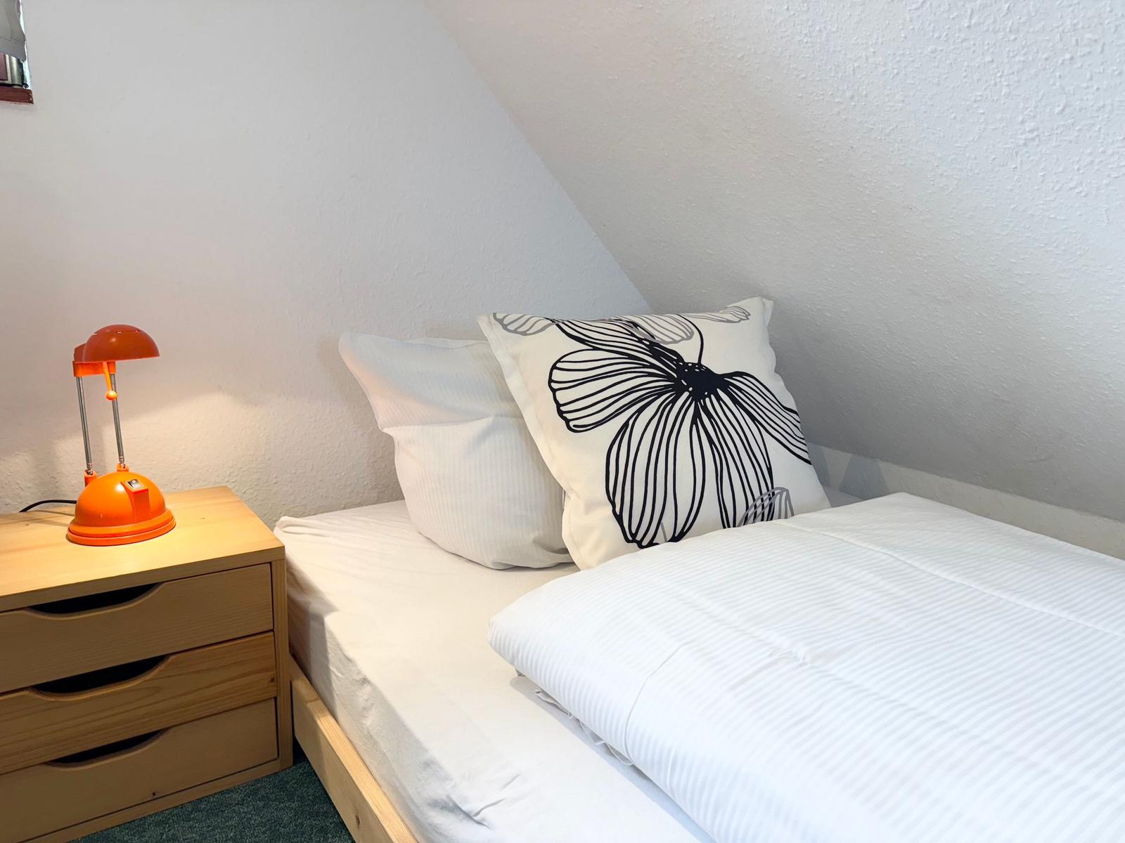 Bedroom with bed, nightstand, and lamp under sloped ceiling