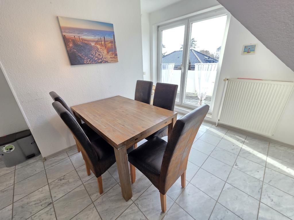 Esstisch mit vier Stühlen, Wandbild und Fenster zur Terrasse.