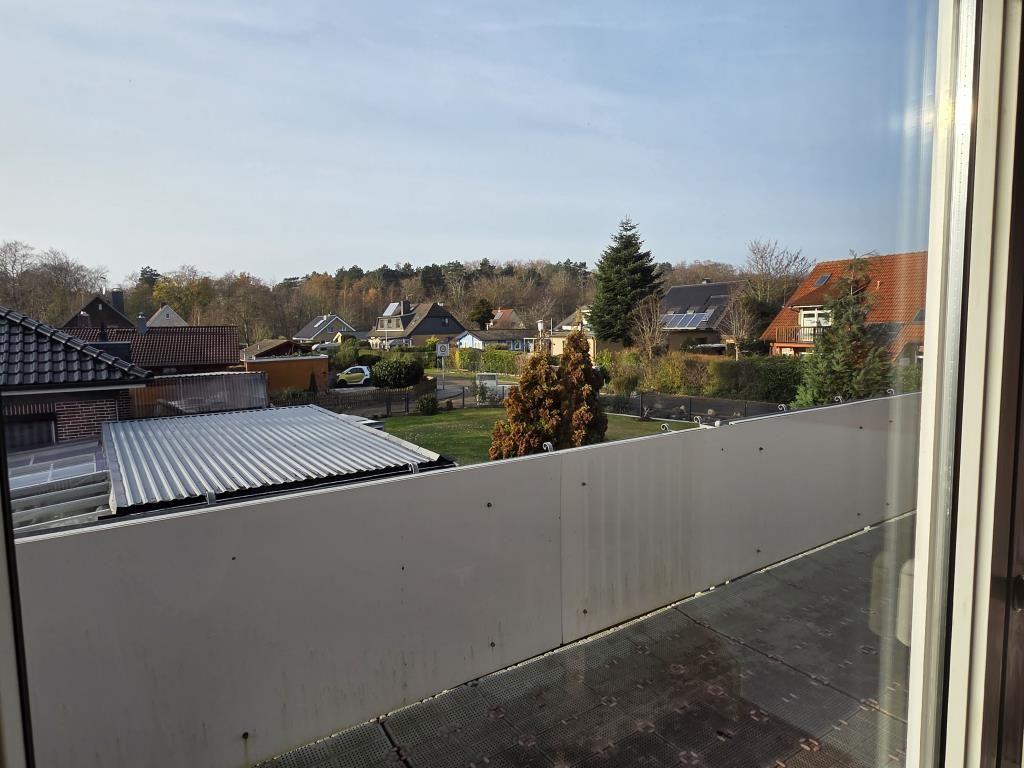 Blick von Balkon auf Wohngebiet mit Bäumen und Häusern unter klarem Himmel