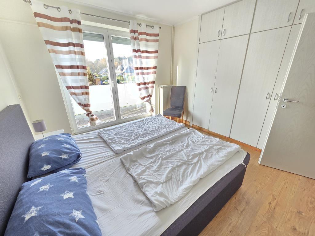 Schlafzimmer mit Doppelbett, Schwebetüren und Kleiderschrank.