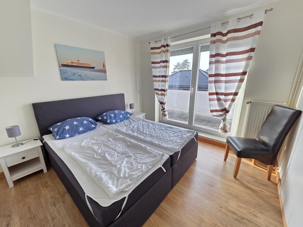 Schlafzimmer mit Doppelbett, Fenster und Stuhl.