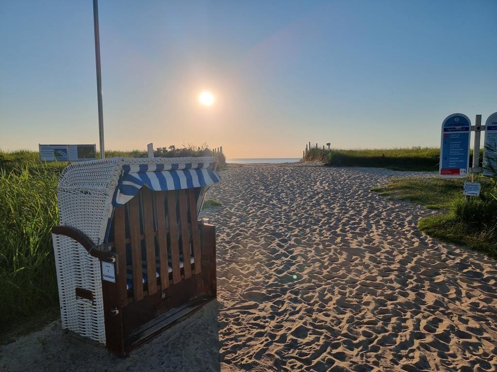 Strandpromenade mit Strandkorb und Sonnenuntergang am Meer