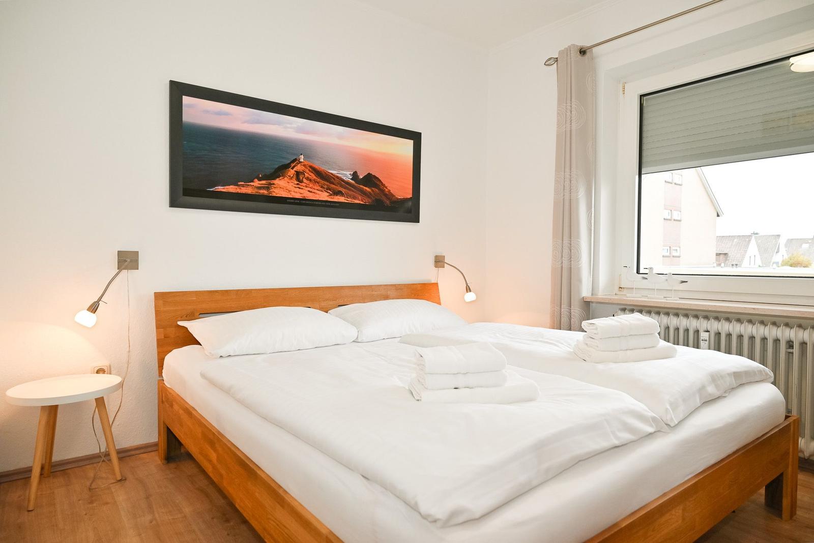 Schlafzimmer mit Doppelbett, Wandbild und Fenster mit Blick.