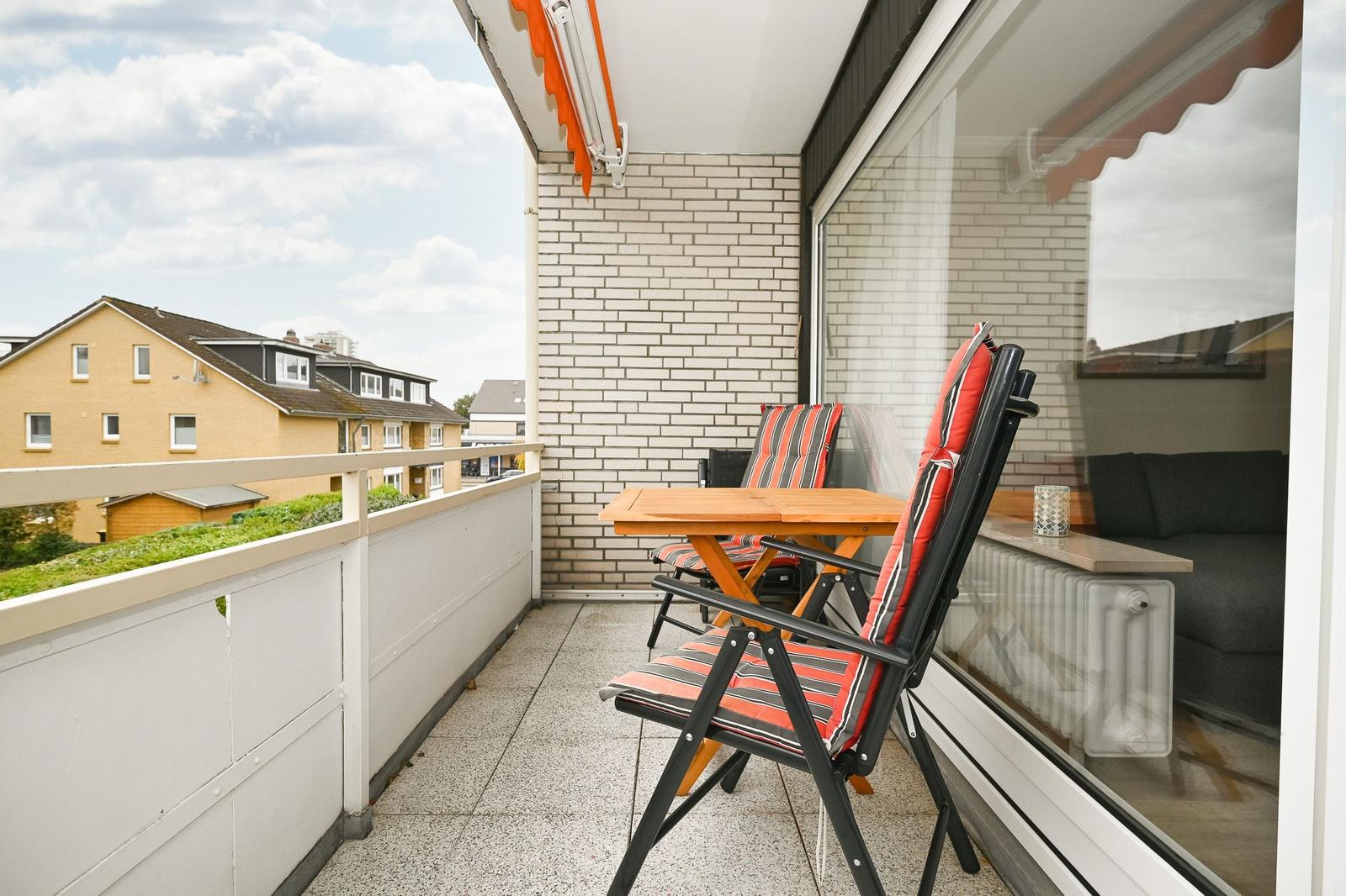 Terrasse mit Tisch, zwei Stühlen und Blick auf Wohngebiet.