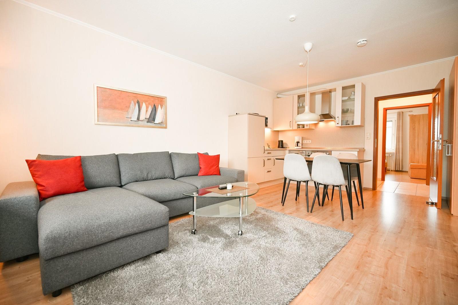 Wohnzimmer mit Sofa, Couchtisch und angrenzender Küche.