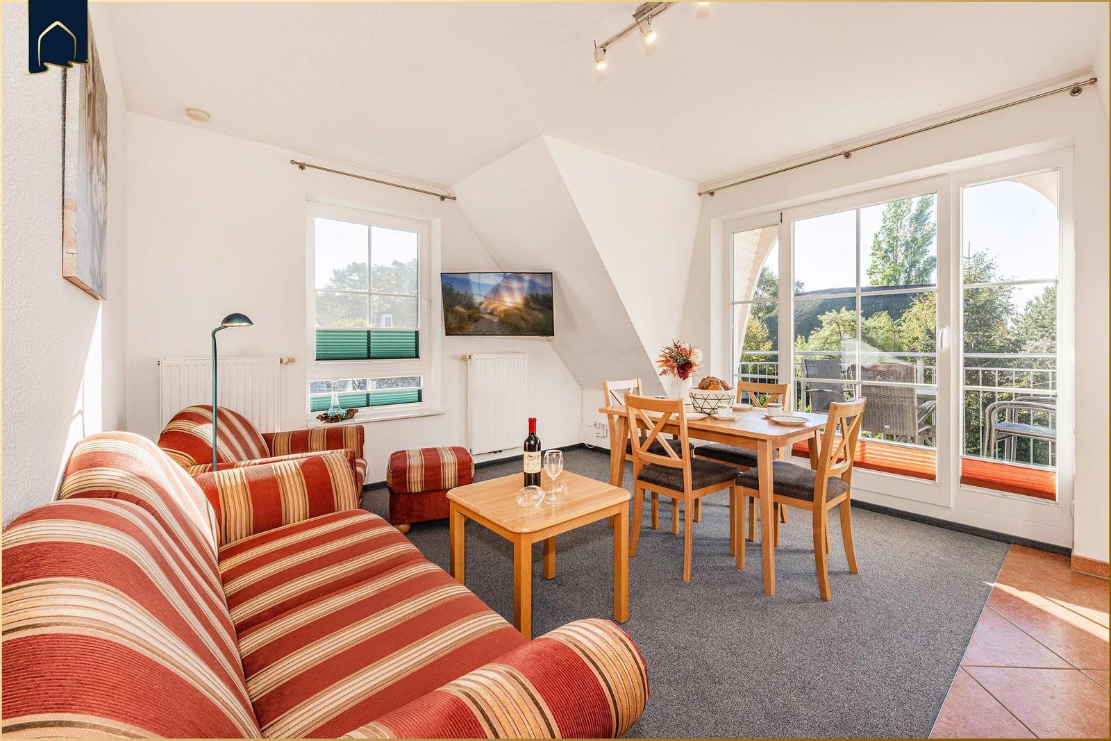 Wohn- und Essbereich mit Sofa, Tisch und Blick auf Balkon.