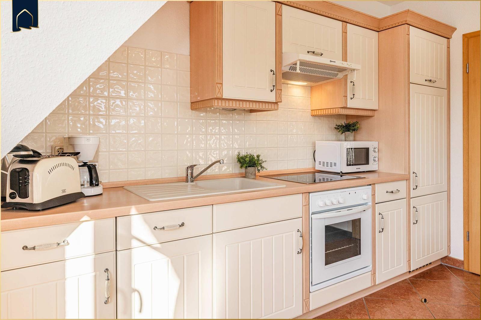 Küche mit weißen Schränken, Edelstahlspüle und integriertem Herd.