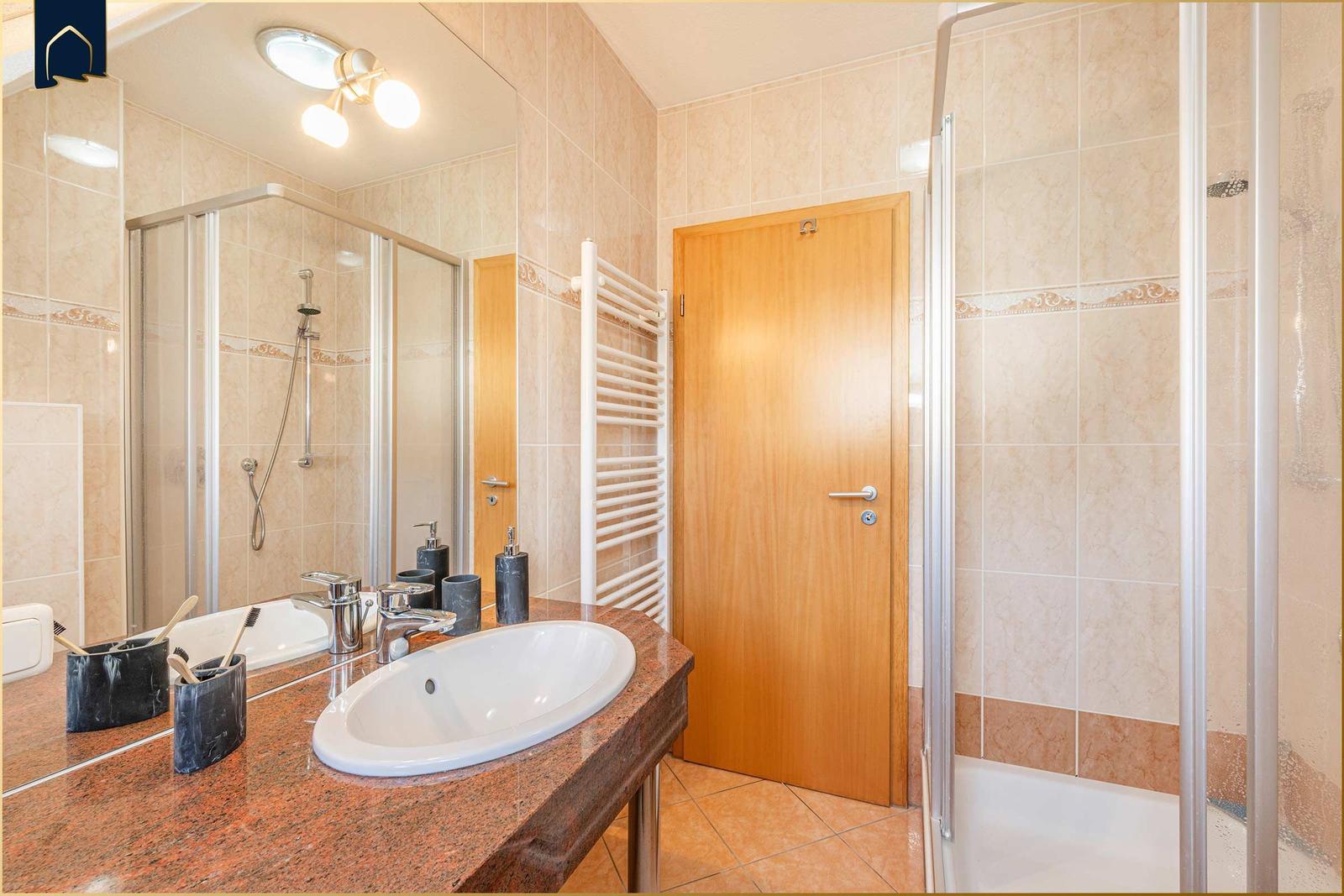 Bad mit Dusche, Waschbecken und Heizkörper