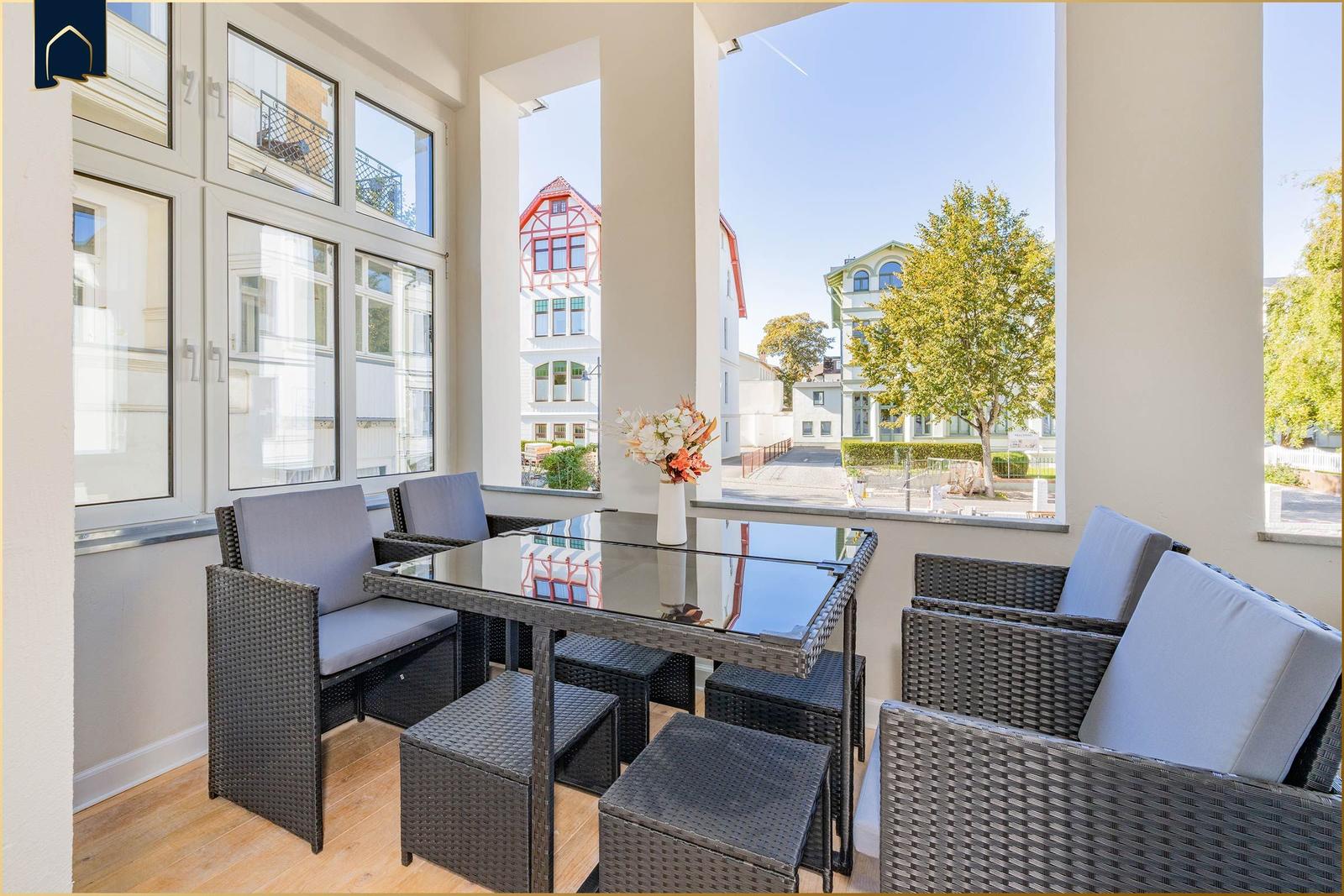Terrasse mit Sitzgruppe und Tisch. Blick auf Gebäude und Bäume.