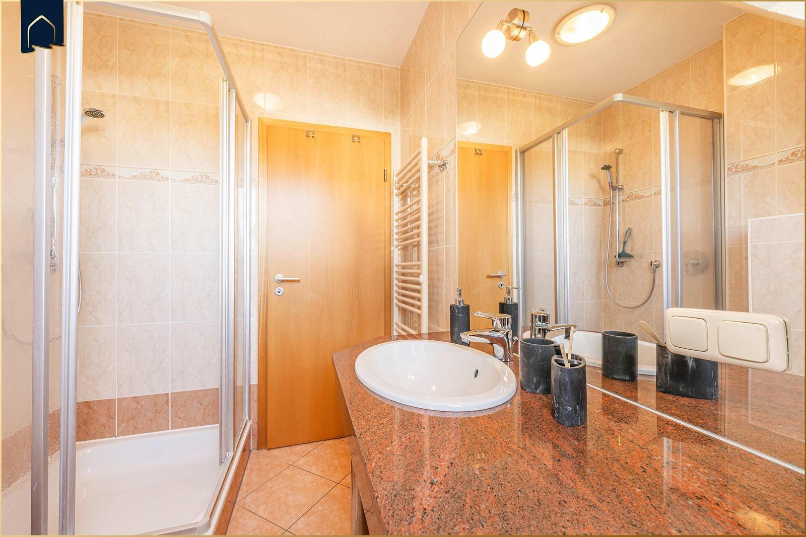 Badezimmer mit Dusche, Waschbecken und Spiegel.