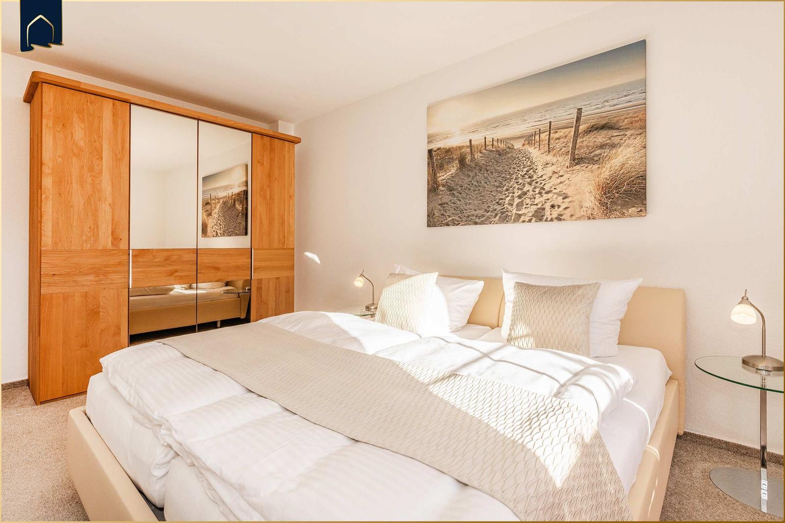 Schlafzimmer mit Bett, Kleiderschrank und Wandbild.