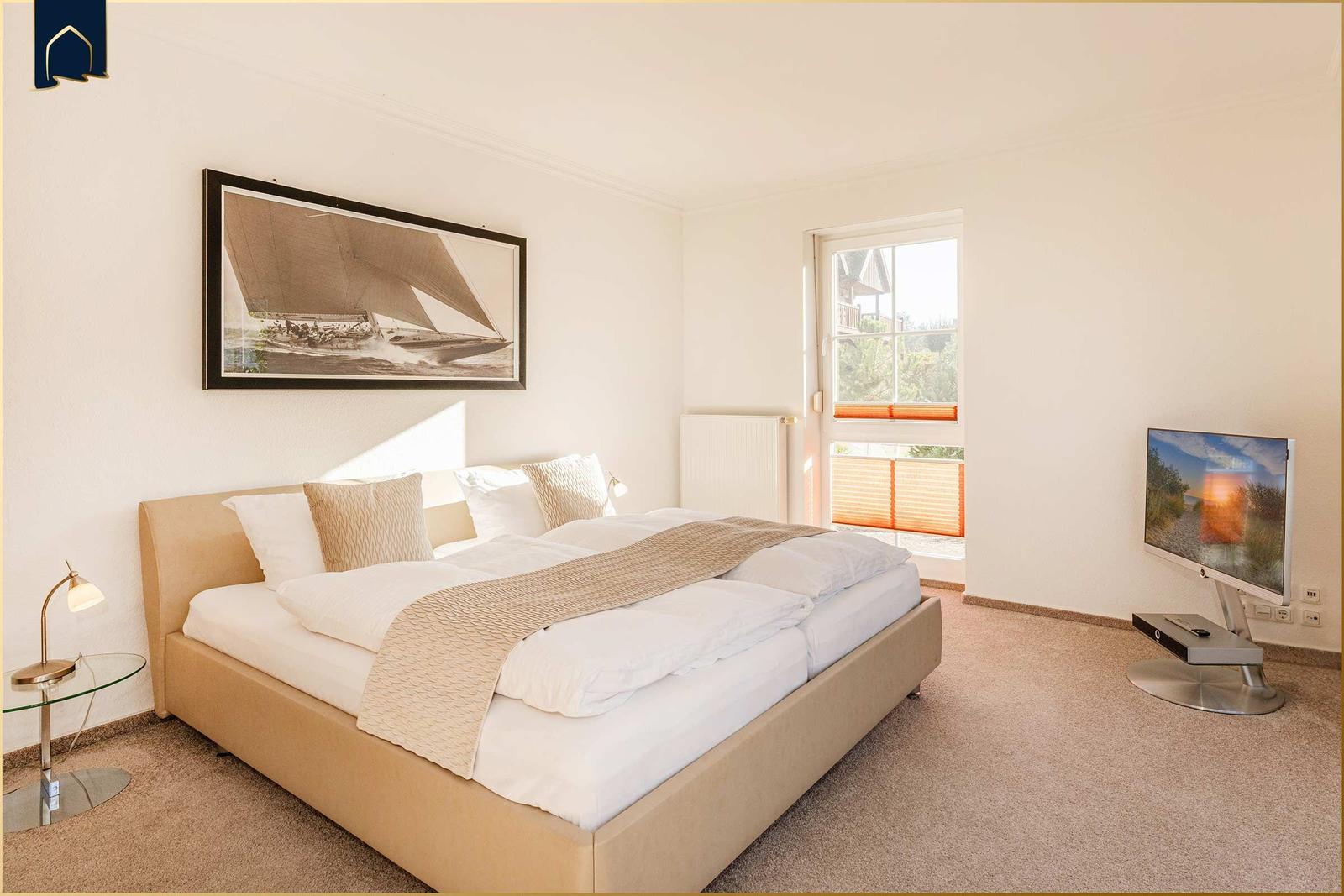 Schlafzimmer mit Doppelbett, Fernseher und Fenster zur Aussicht.