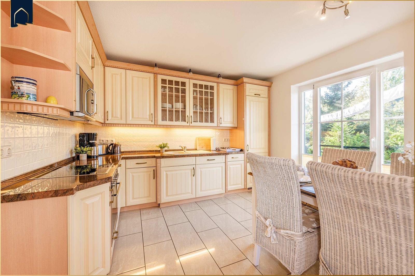 Küche mit Essbereich, Holzschränken und Blick auf Garten.