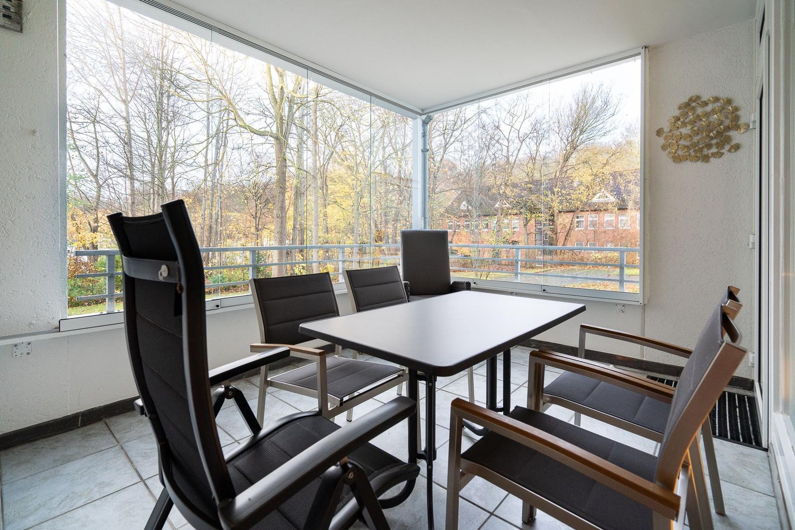 Terrasse mit Tisch und Stühlen, Blick auf Bäume und Gebäude