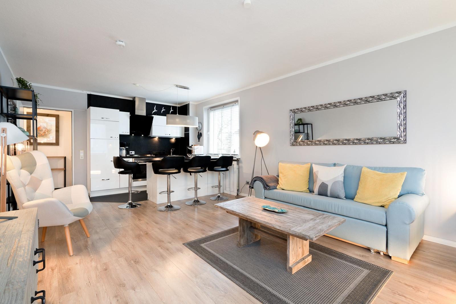 Wohnbereich mit Sofa, Couchtisch und Küchenzeile mit Barhockern.