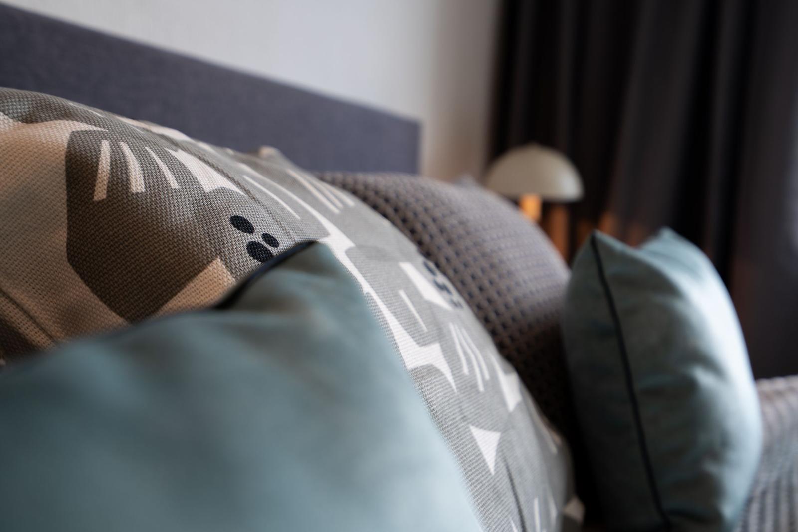 Bettkopfteil mit Kissen in Grau- und Blautönen