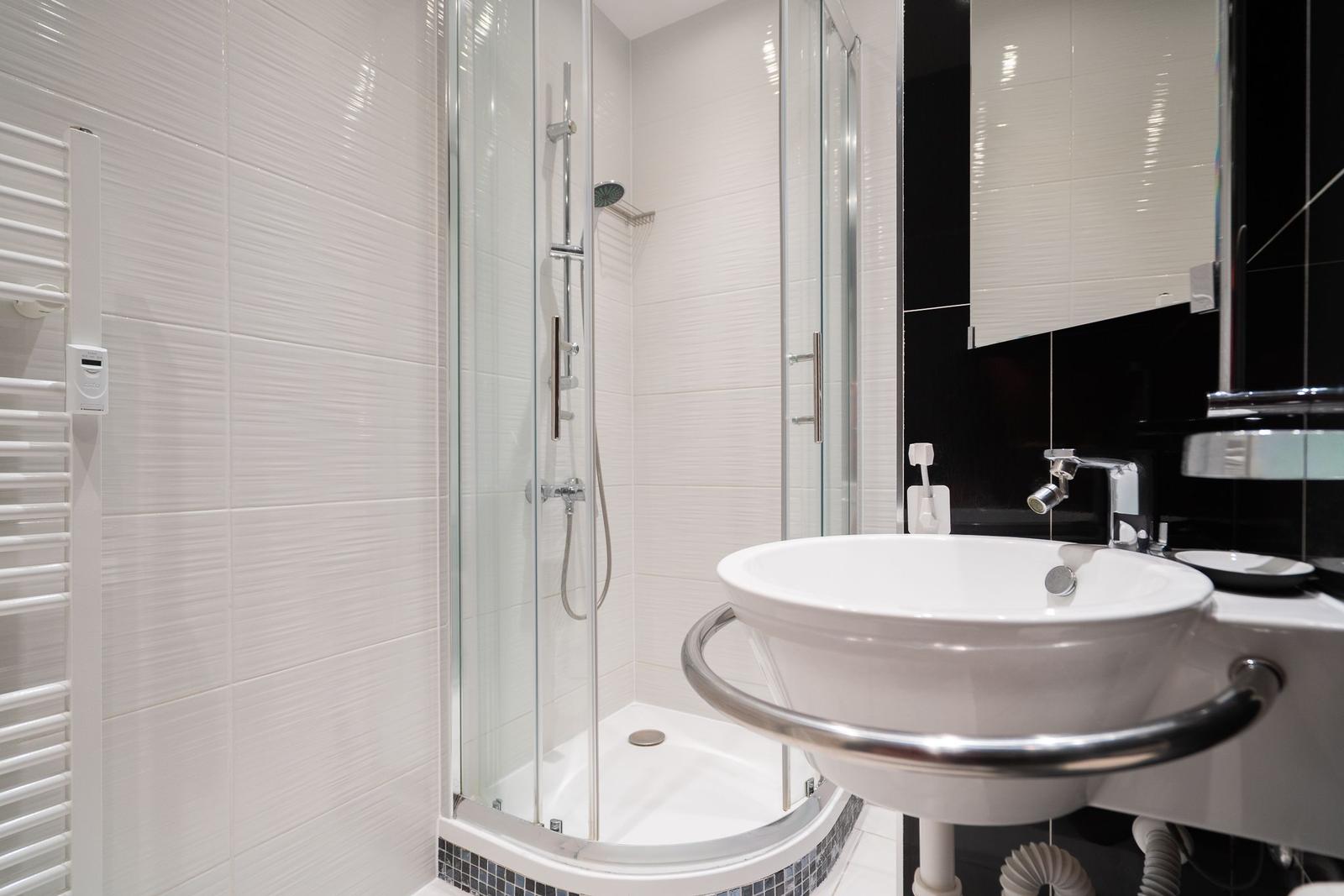 Badezimmer mit Dusche, Waschbecken und Heizung.