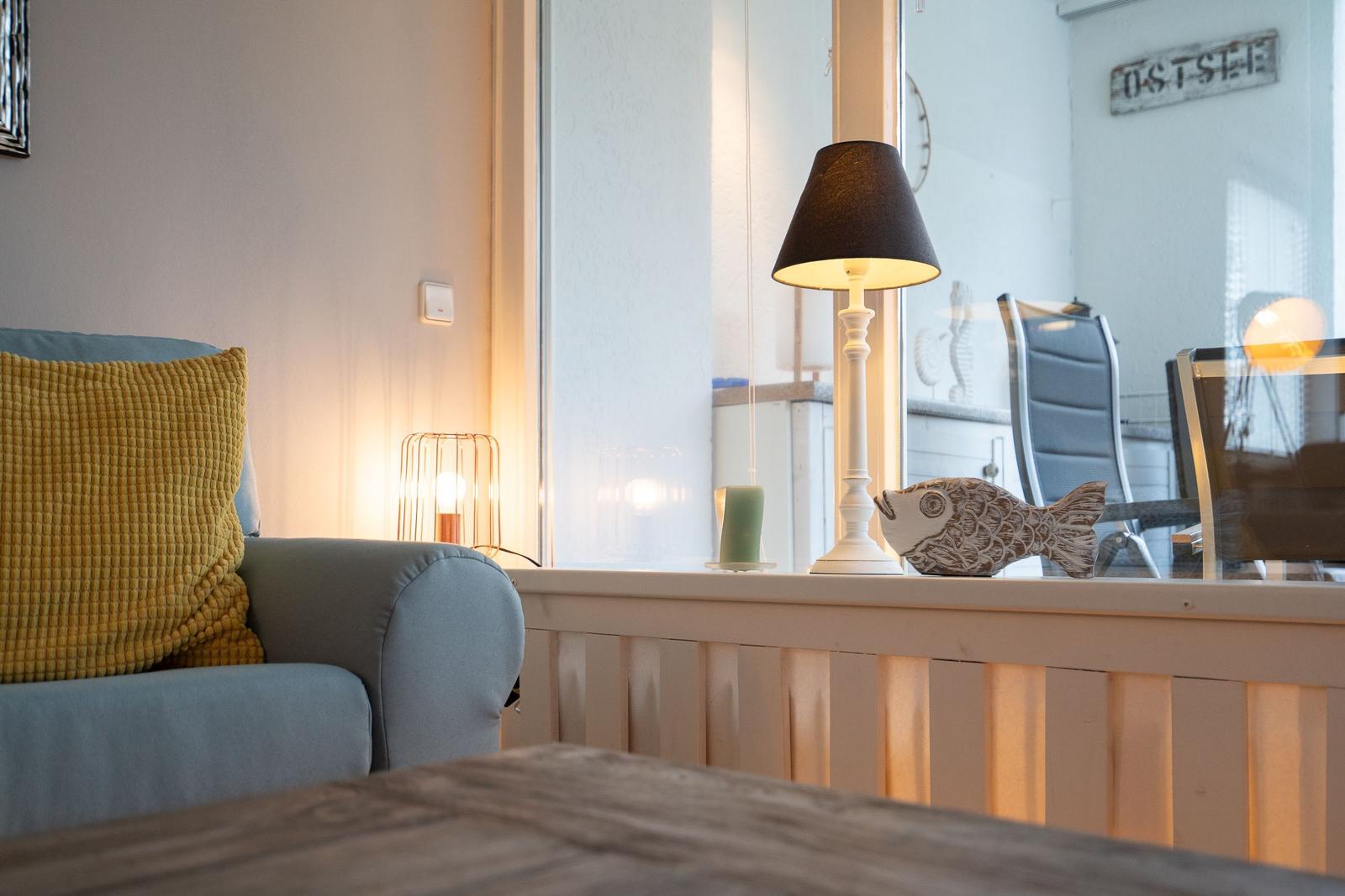 Ein Raum mit Sofa, Lampe und Fischdekoration an Fensterbank