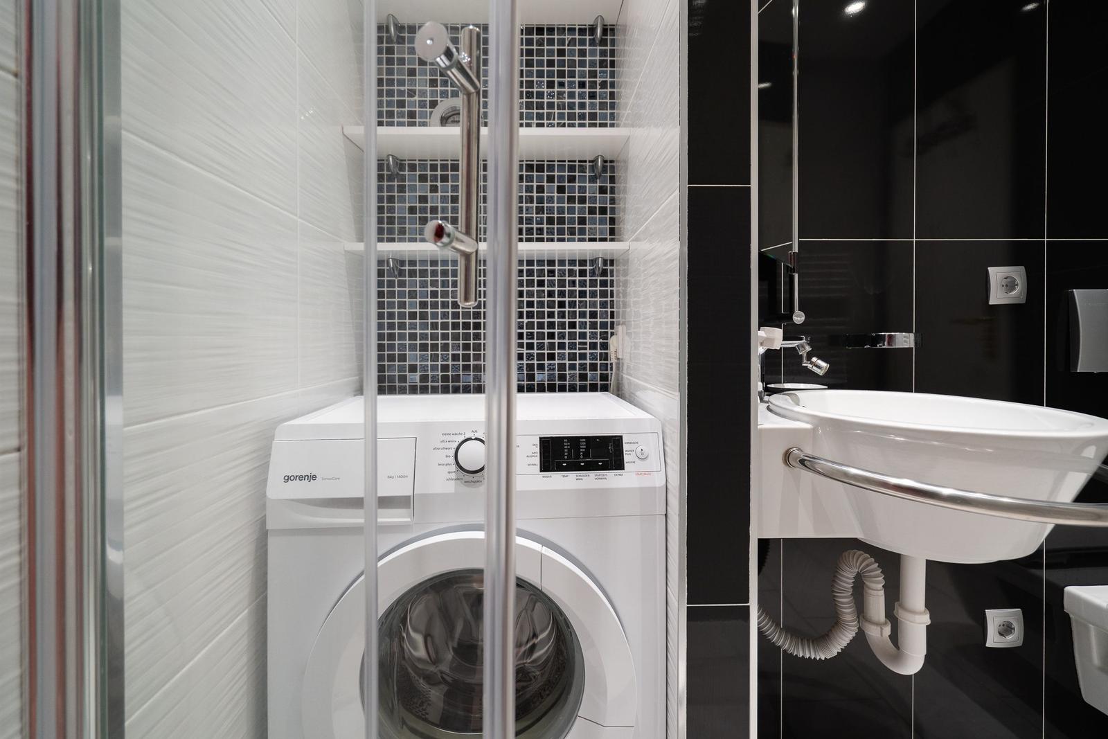 Waschmaschine im Bad mit Dusche und Waschbecken.