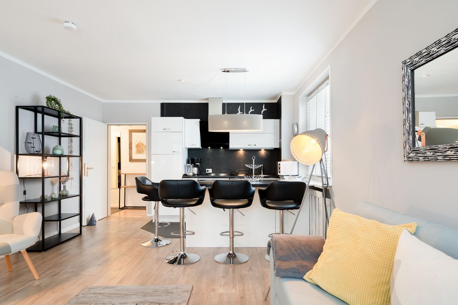 Moderne Küche mit Barhocker und Wohnbereich mit Sofa und Beistelltisch.