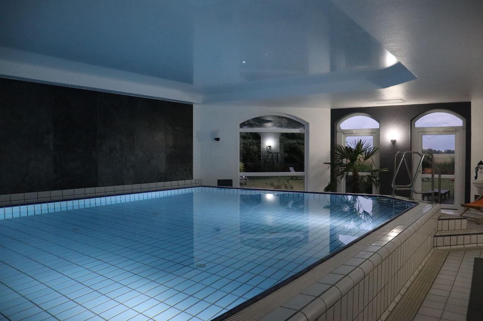 Innere Schwimmhalle mit Pool und Fenstern zur Aussenseite.