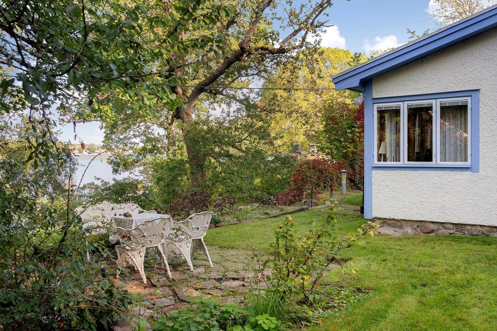 Haus mit Terrasse, Garten und Blick auf Wasser.