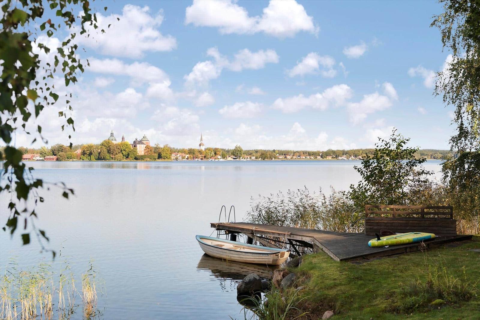 Boot liegt am Steg. Blick auf Wasser und Stadt mit Kirchen.