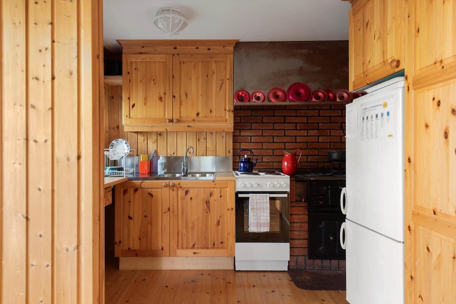 Küche mit Holzschränken, Backofen und Kühlschrank.