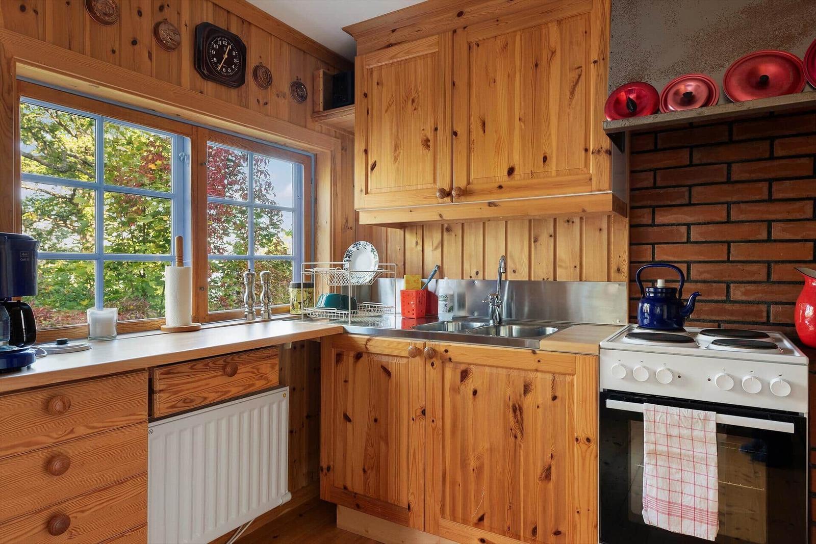 Küche mit Holzmöbeln, Fenster und Herd. Aufbewahrung und Arbeitsfläche.