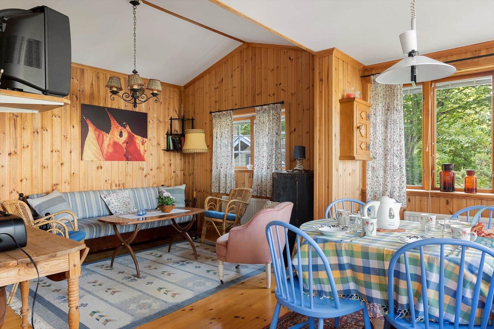 Wohn- und Essbereich mit Holzwand, Sofa, Tisch und Stühlen.