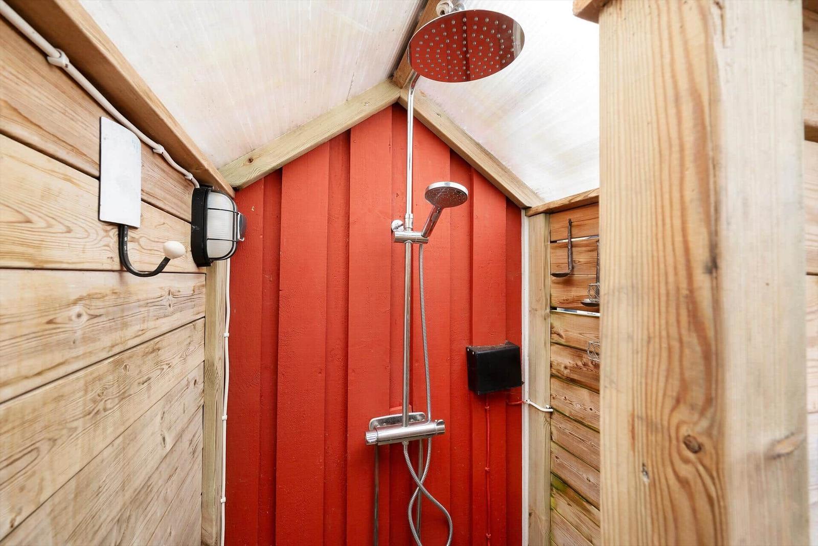 Außen-Dusche mit roter Wand und Edelstahl-Duschkopf
