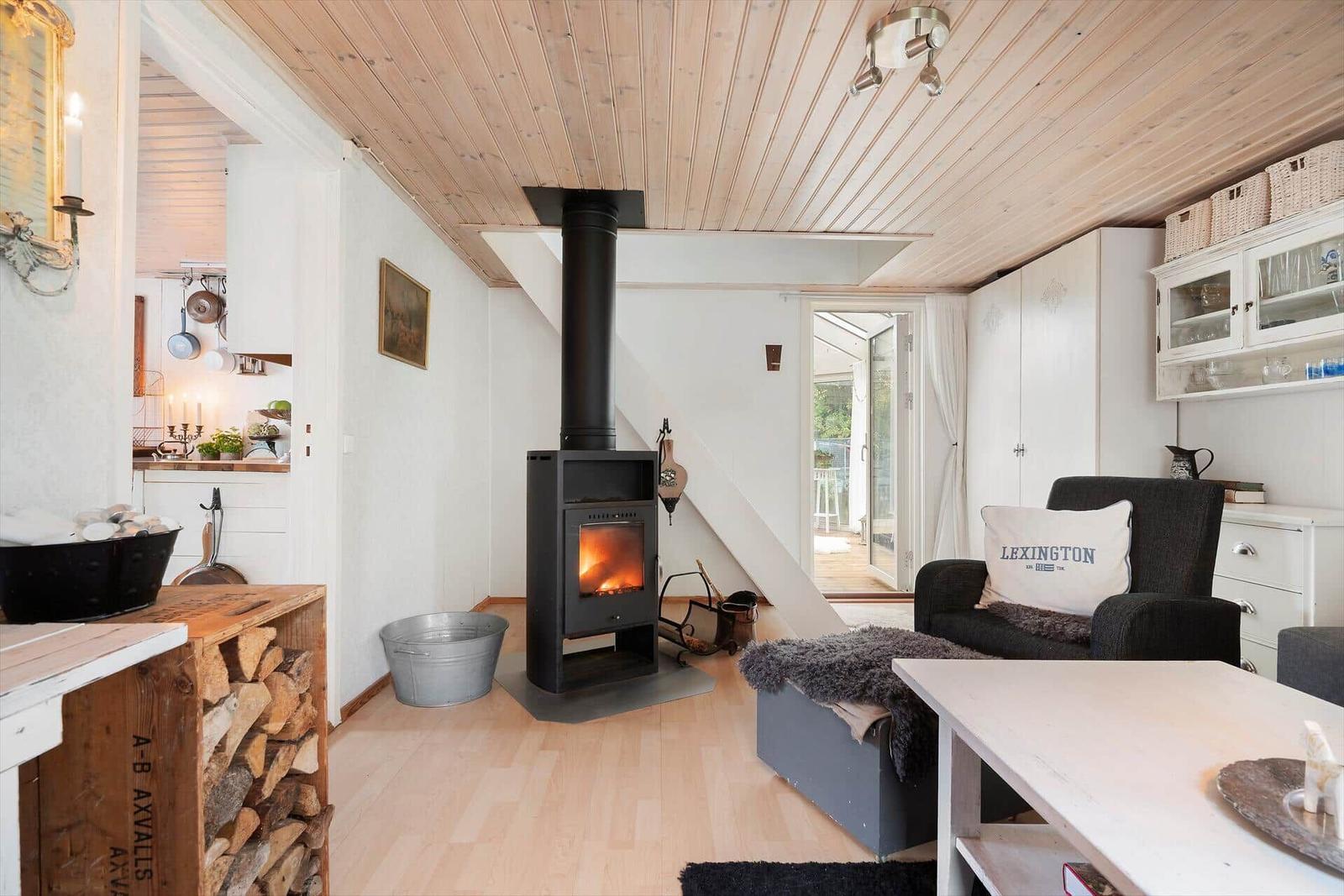 Wohnraum mit Kamin, Sofa und Blick auf Balkon.