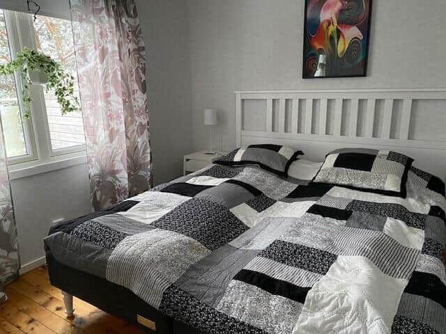 Schlafzimmer mit Doppelbett, Fenster und Wandbild.