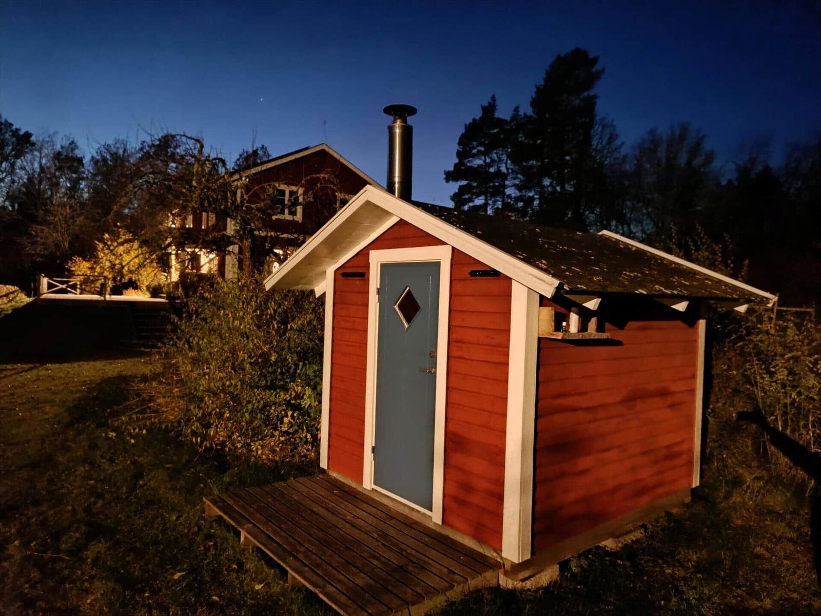 Roter Holzaufbau mit blauer Tür und Schornstein im Freien.