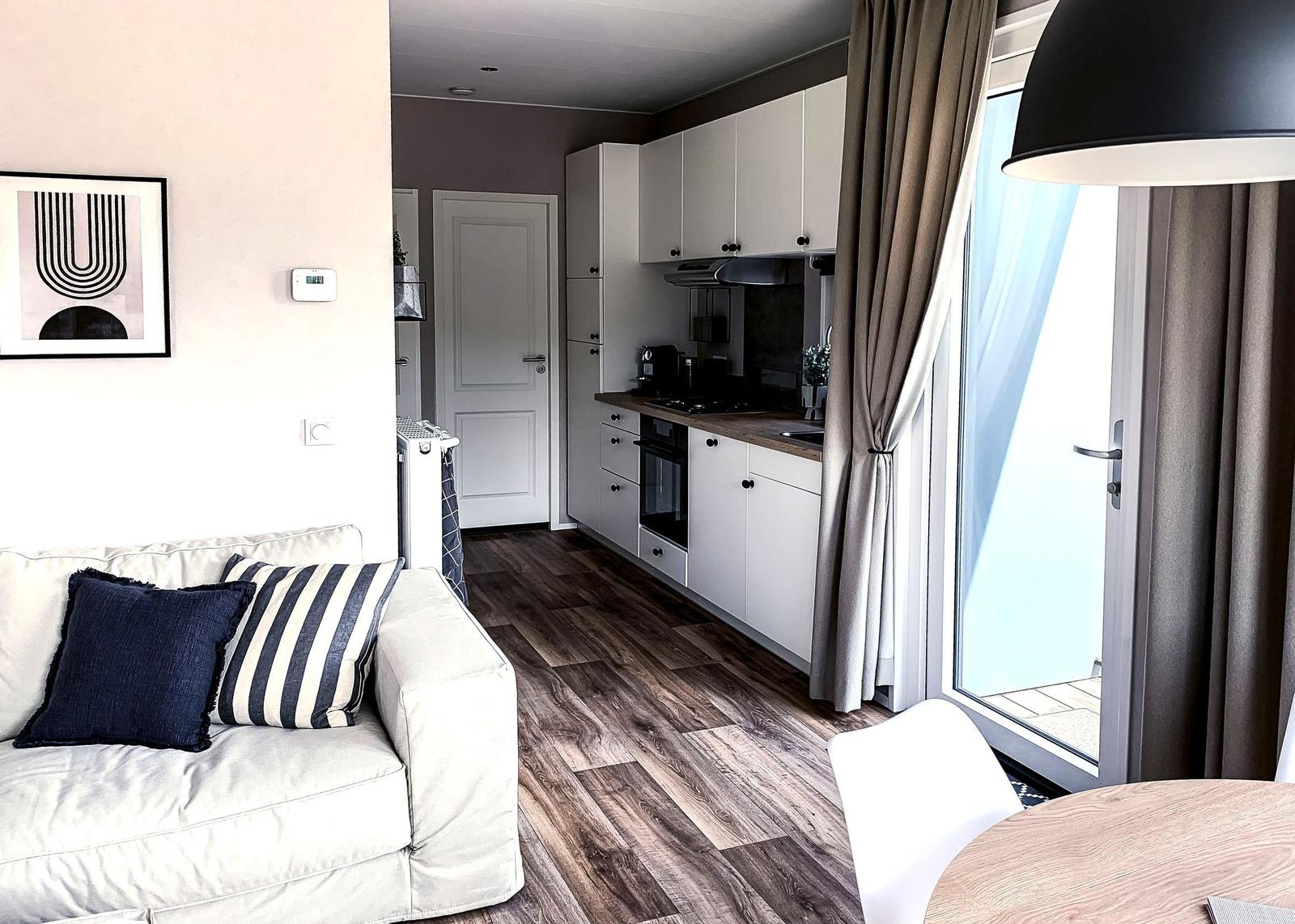 Wohnbereich mit Sofa, Küche und Balkontür.