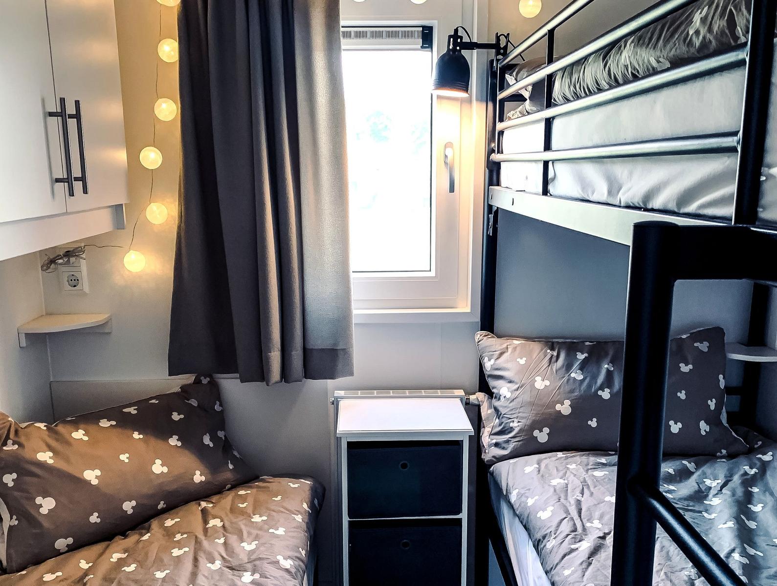 Zimmer mit Doppelstockbett und Schlafcouch, Fenster und Lichterkette.