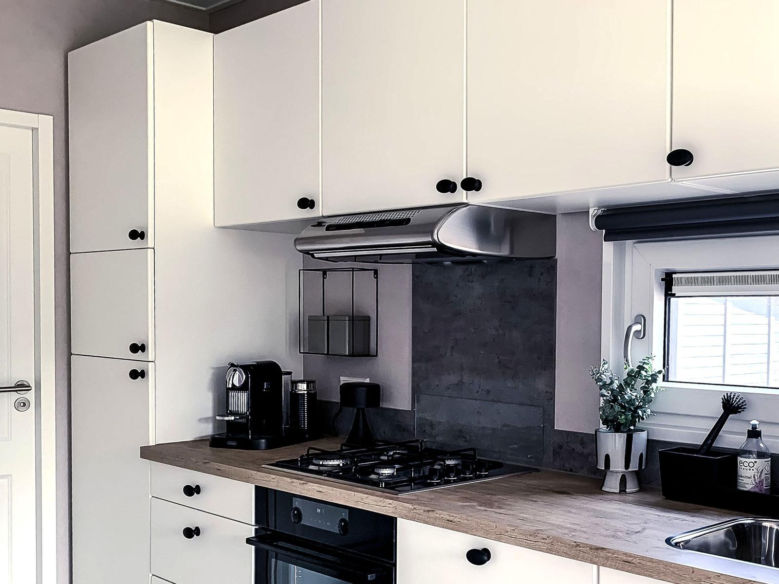 Küche mit weißen Schränken, Holz Arbeitsplatte und Gasherd.