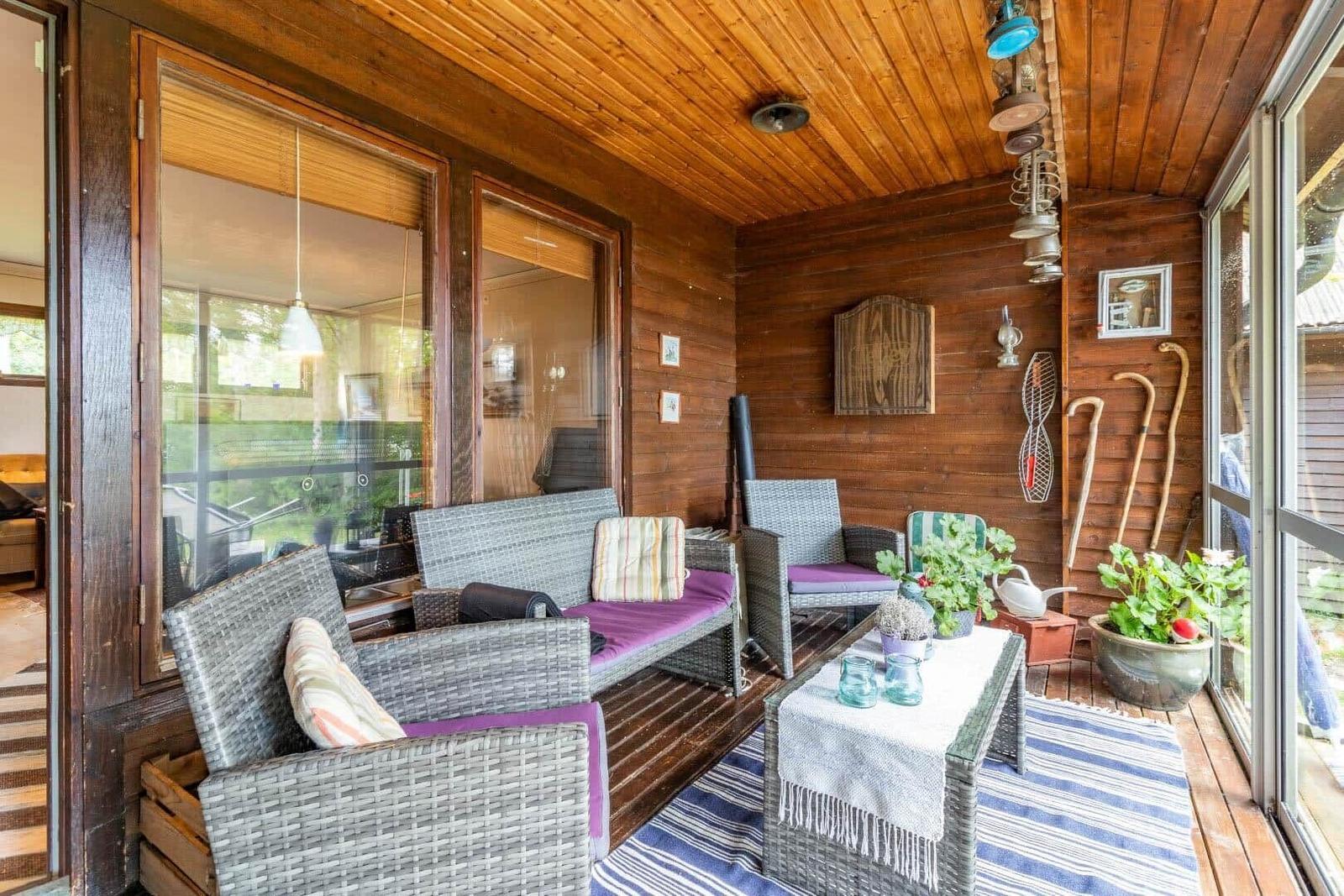 Terrasse mit Sitzgruppe, Pflanzen und Holzwand. Durchgehende Glasfront.