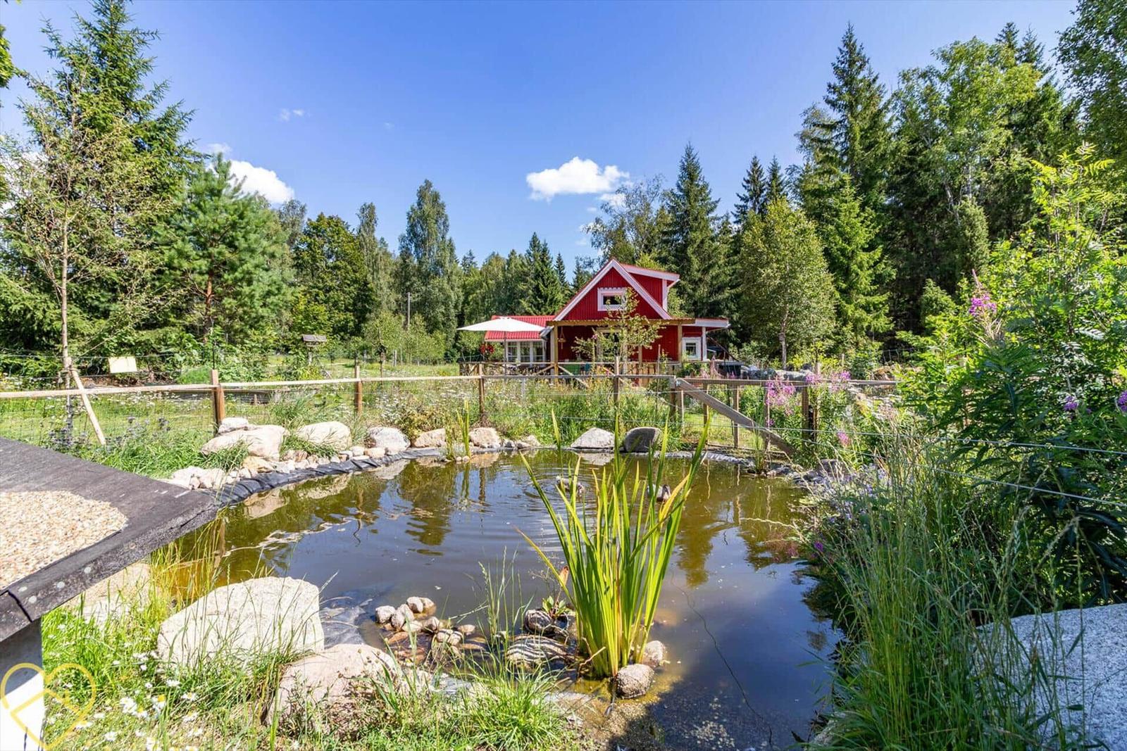 Rotes Haus mit Pool und Garten in Waldnähe.