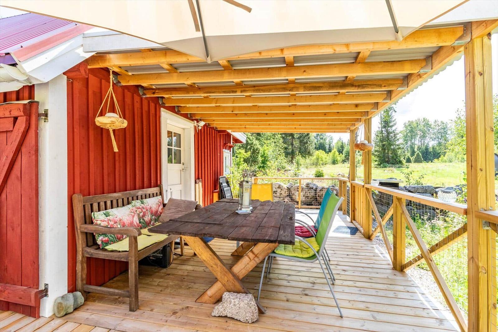 Terrasse mit Tisch, Bänken und Sitzgelegenheiten unter einem Dach.