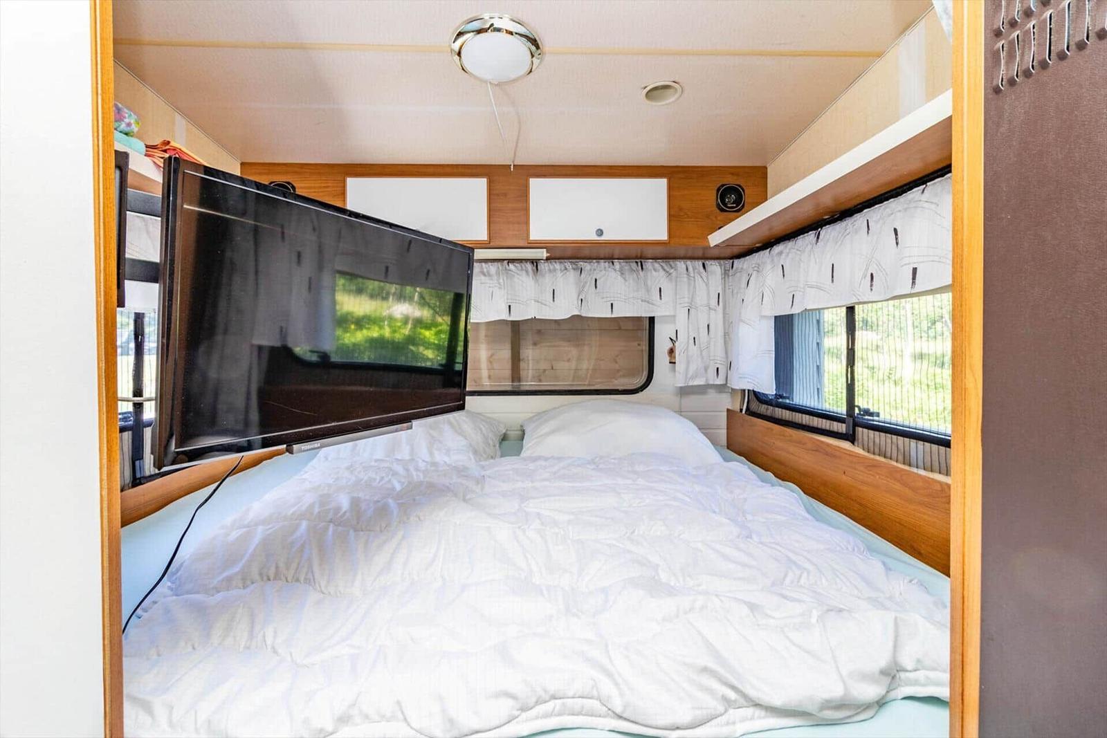 Schlafzimmer mit Bett, TV und Fenstern.