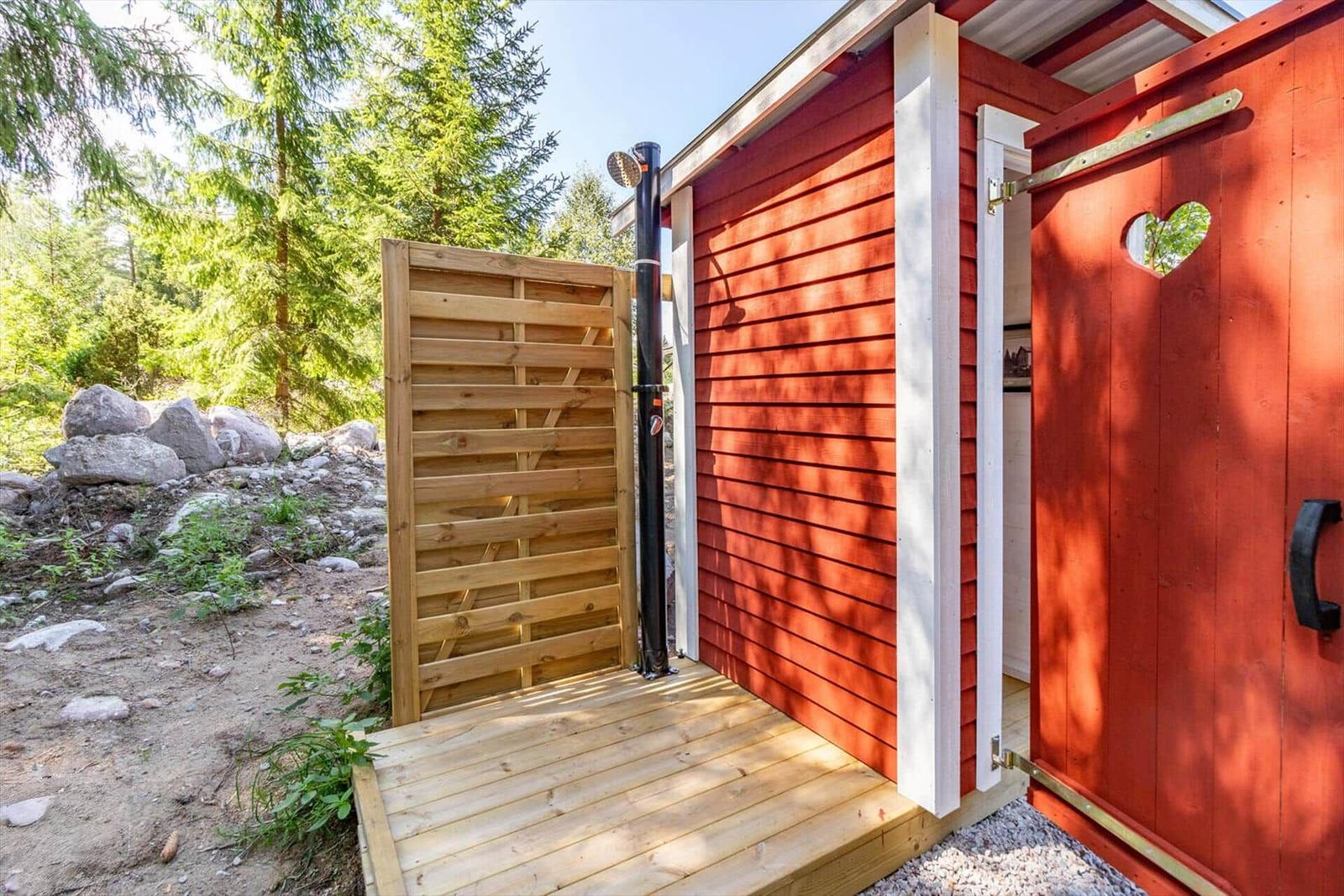 Roter Holzausgang mit Herzförmigem Fenster und Duschbereich im Freien.