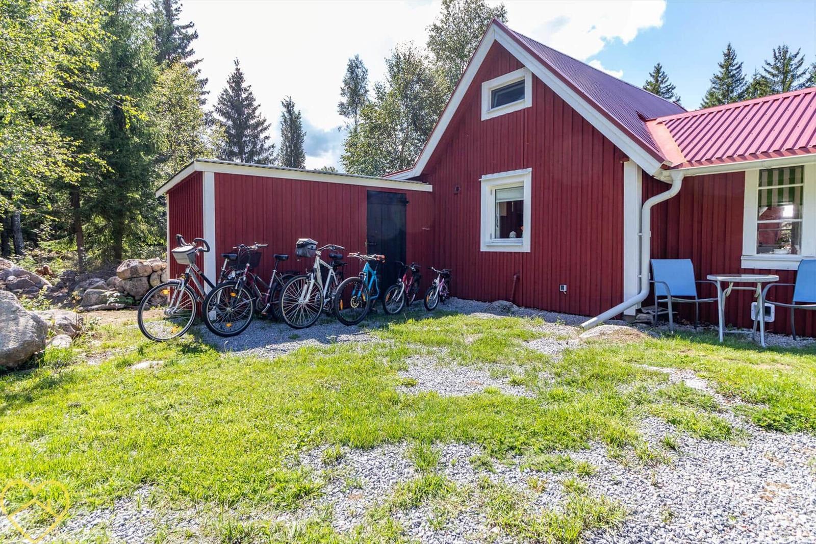 Rotes Holzhaus mit Fahrrädern und Sitzgruppe im Freien.
