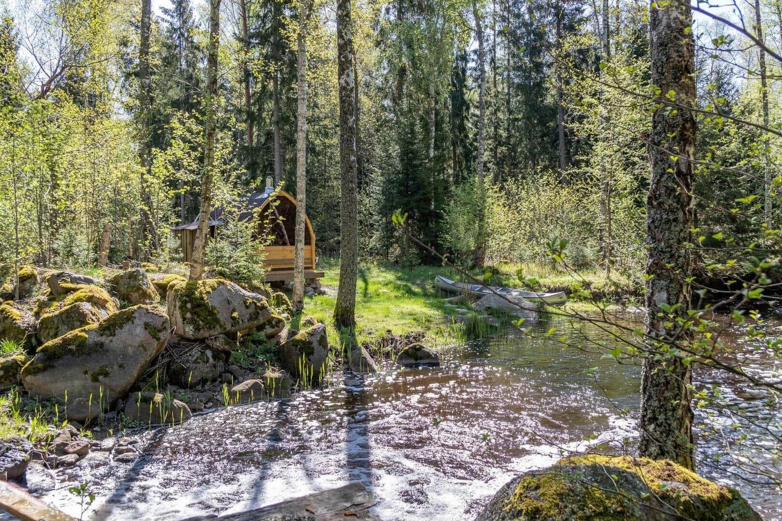 Holzhütte am Fluss mit Kanu und umgeben von Bäumen.