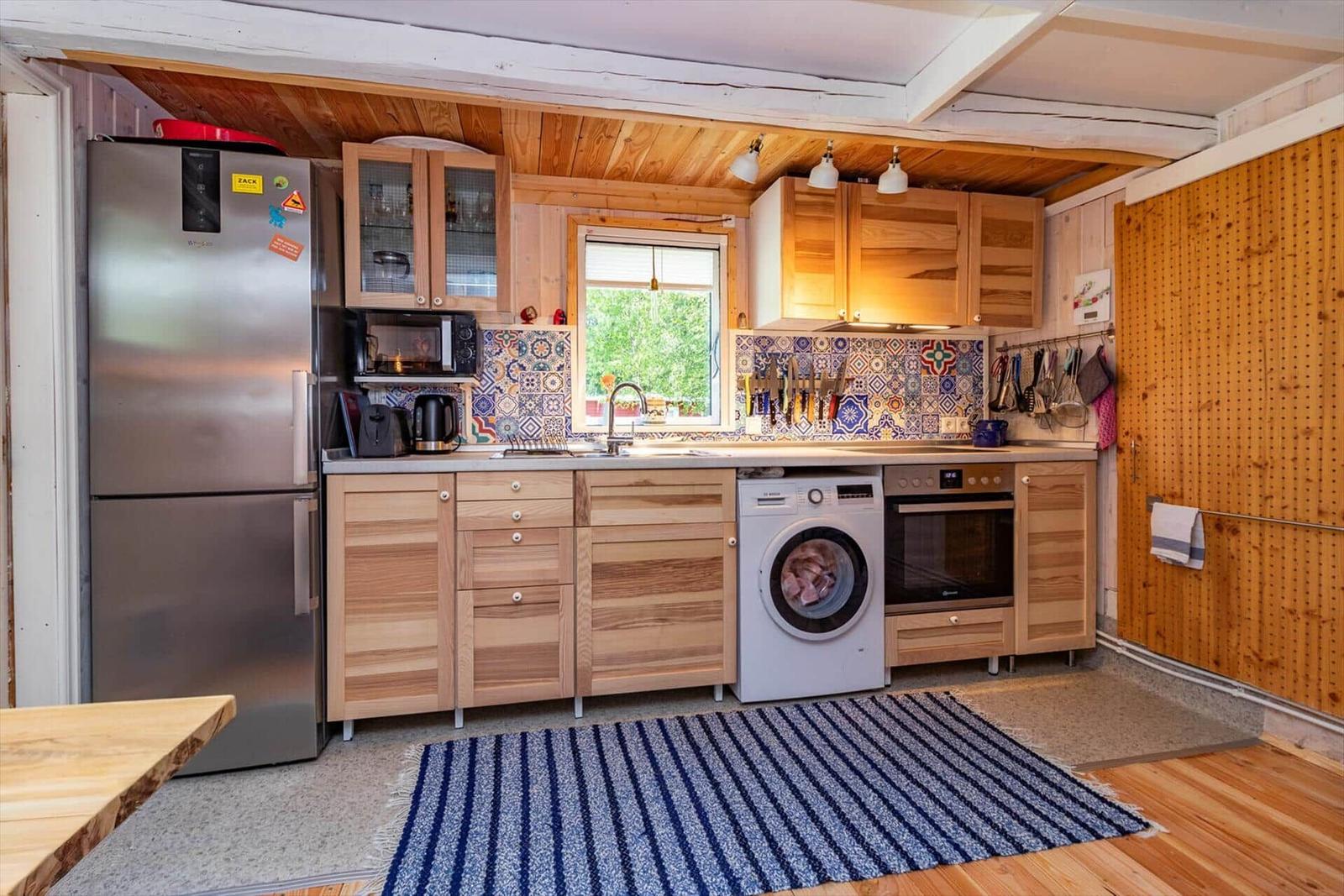 Küche mit Holzmöbeln, Spüle, Waschmaschine und Kühlschrank.