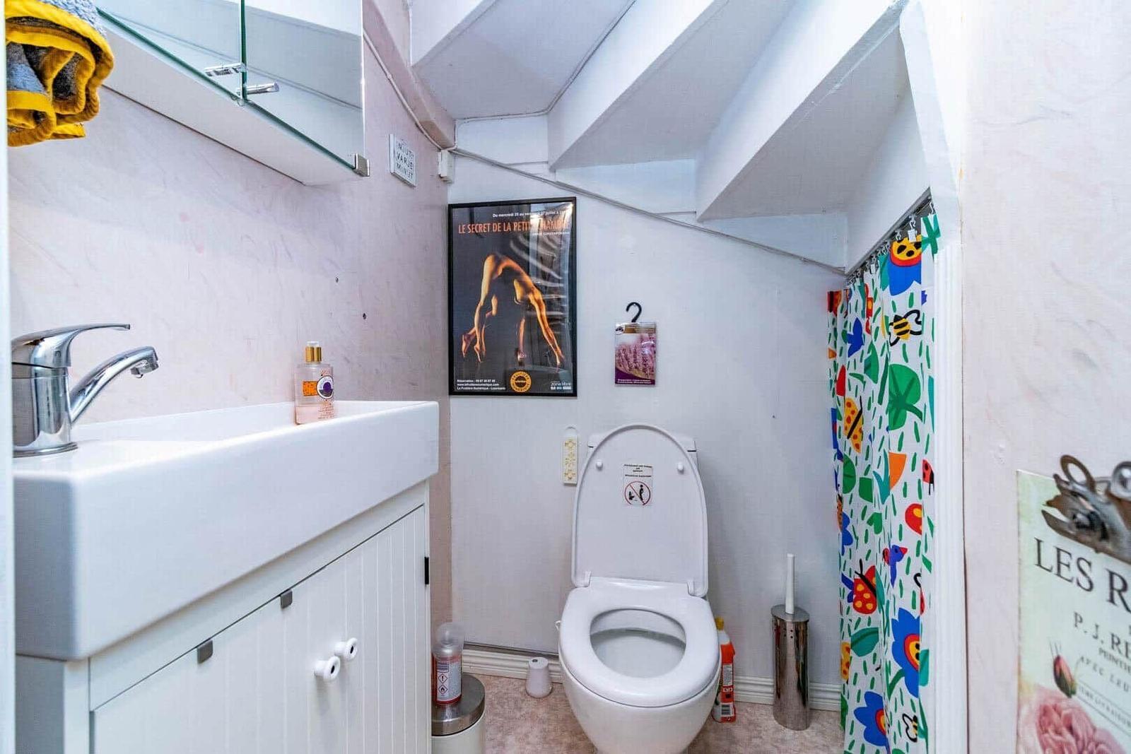 Badezimmer mit Toilette, Waschbecken und buntem Duschvorhang.