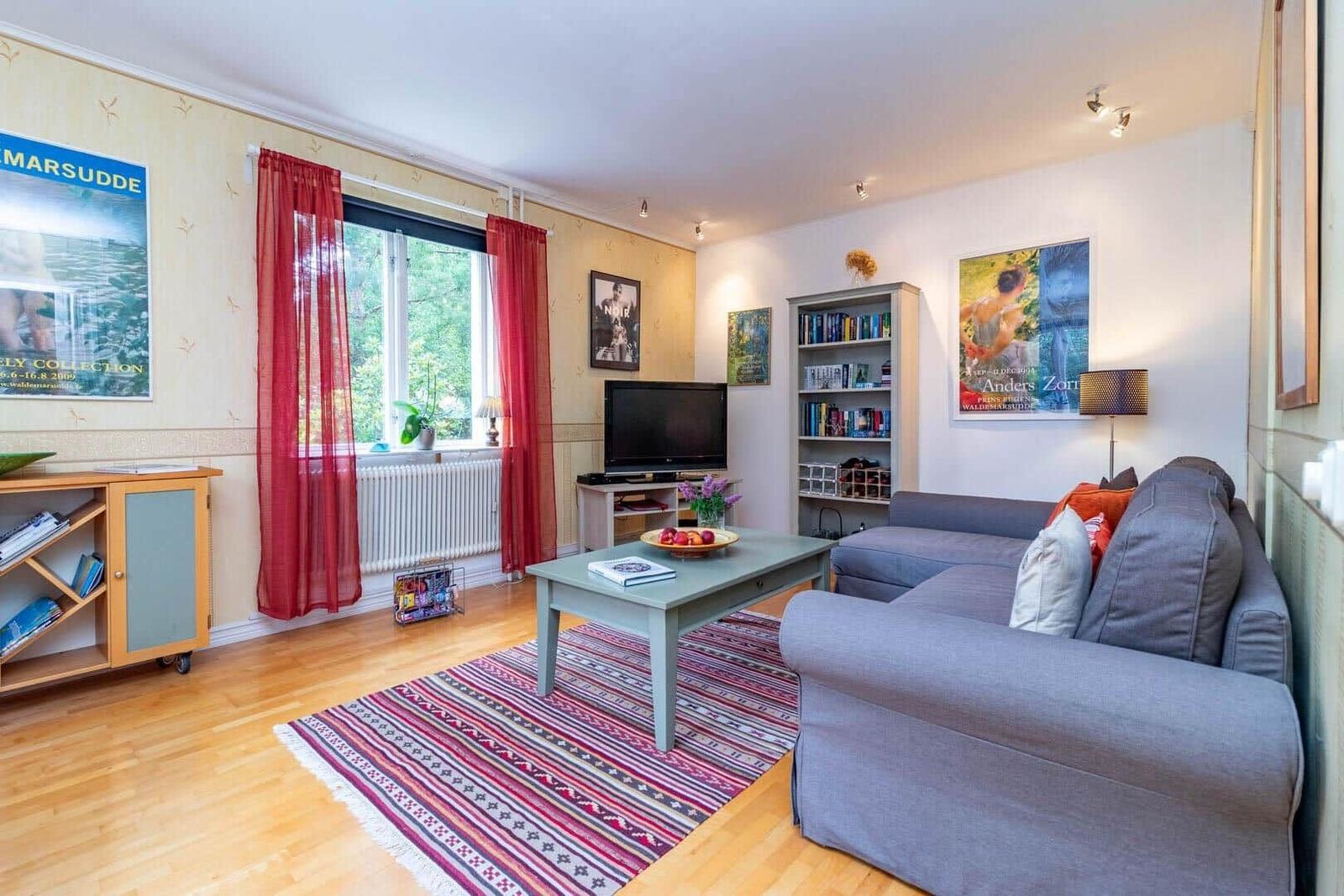 Wohnzimmer mit Sofa, Couchtisch und Fenster mit roten Vorhängen.