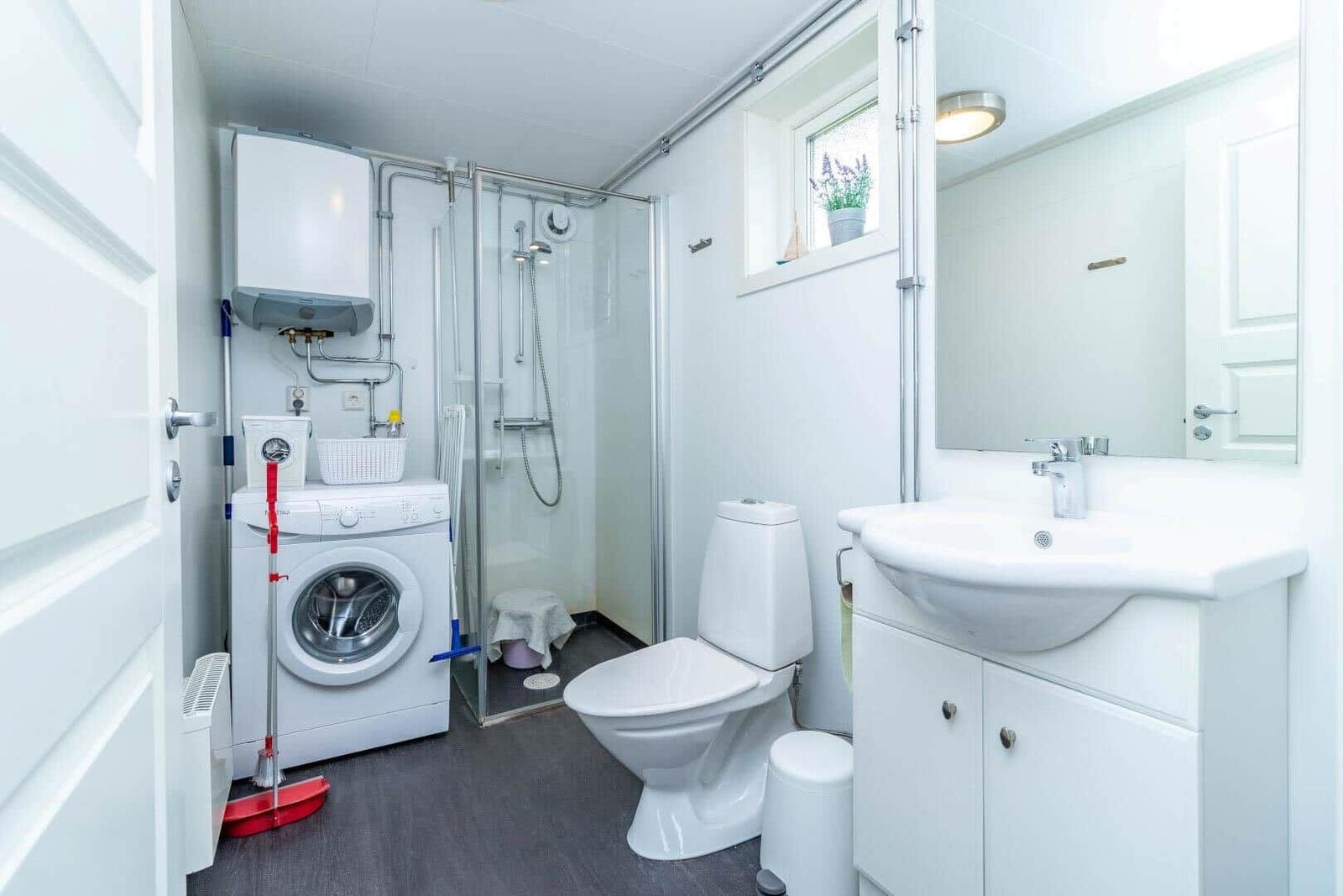 Badezimmer mit Dusche, Toilette, Waschmaschine und Waschbecken