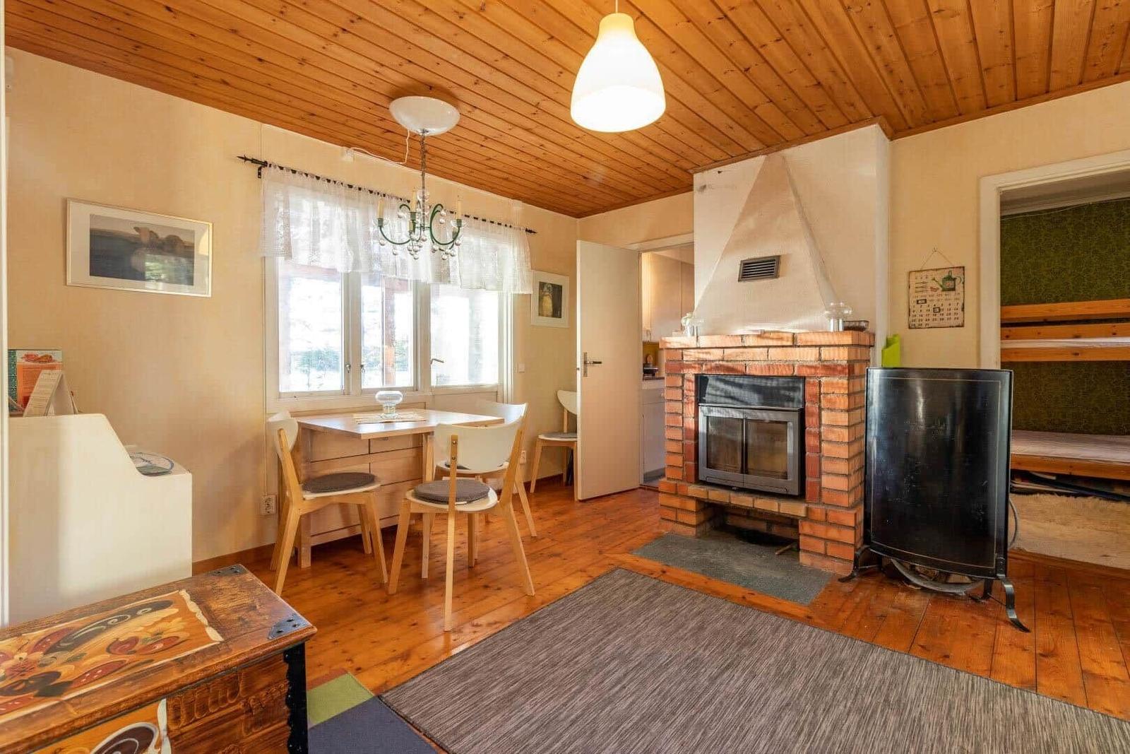 Wohnzimmer mit Kamin, Esstisch und Holzboden.
