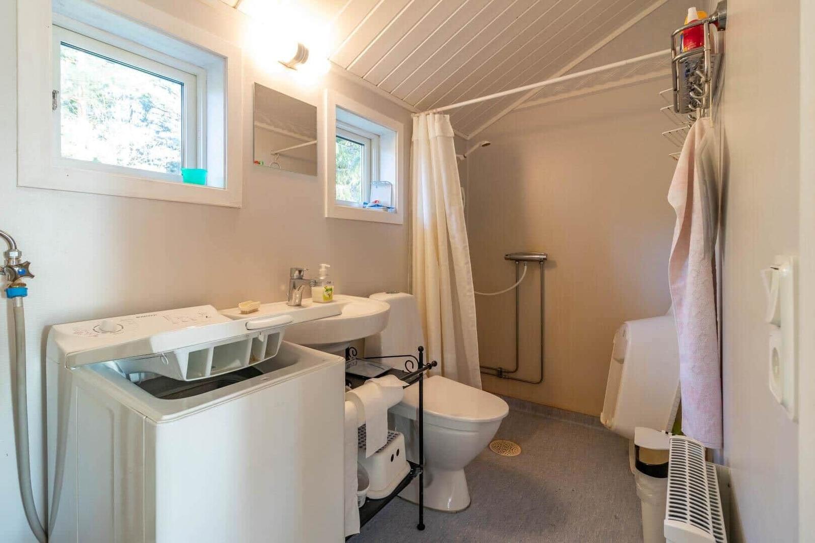 Badezimmer mit Waschmaschine, Toilette und Dusche.